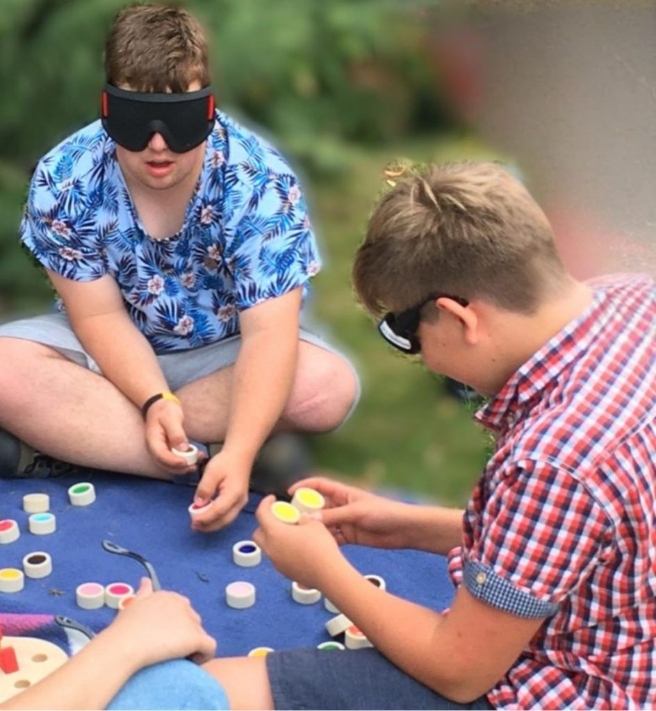 Zwei Kinder haben die Augen verbunden und tasten nach Bausteinen